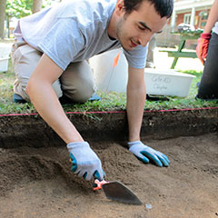 Colour photograph of a trainee archaeologist during the discovery of a pipe bowl.