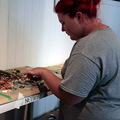 Colour photograph of a young trainee archaeologist identifying artifacts.