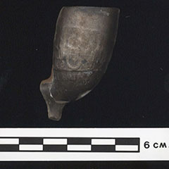 Photographie couleur d'un fourneau de pipe en terre cuite. La pièce est noircie.