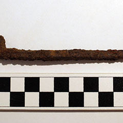 Colour photograph of a rusty forged iron nail.