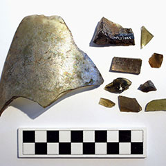 Colour photograph of ten glass pieces. They all have different sizes and shapes. The Borden Code is visible on one piece.