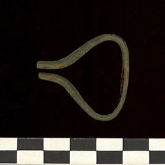 Colour photograph of a small instrument made of copper alloys. The structure is curved on its right side and closer on its left side.