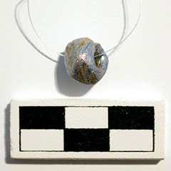 Colour photograph of a faceted glass blue bead on a thread.