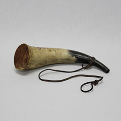 Colour photograph of a black and white horn. A rope is attached to it.