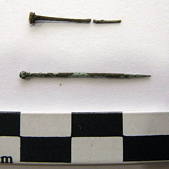 Photographie couleur de deux aiguilles rouillées en cuivre. Une est cassé en deux, l'autre est intacte.