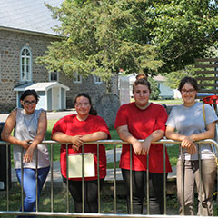 Colour photograph of four trainee archaeologists leaning on a metal barrier.