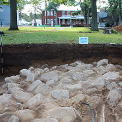 Colour photograph of several squared stones forming a housing foundation. The Musée des Abénakis is also visible.
