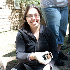 Colour photograph of a young trainee archaeologist holding a shoe buckle in her hand.