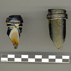 Photographie couleur de deux goulots brisés de bouteilles de verre.